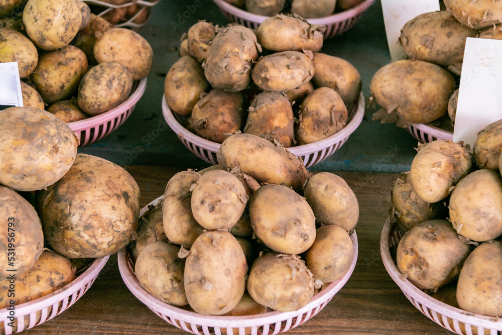 Fresh potatoes in plastic plates on the counter. Selling potatoes at the farmers' market. Close-up. Vegetable trade. Fresh potatoes in plastic plates on the counter. Selling potatoes at the farmers' market. Close-up. Vegetable trade.