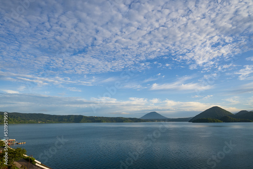 青空と流れゆく白い雲を映す洞爺湖面 © eddiemgg