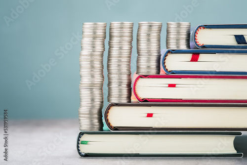 Closeup heaps of money coins arranged on the pile of textbooks step by step, education loans, scholar, and investment, or education subsidy money concept