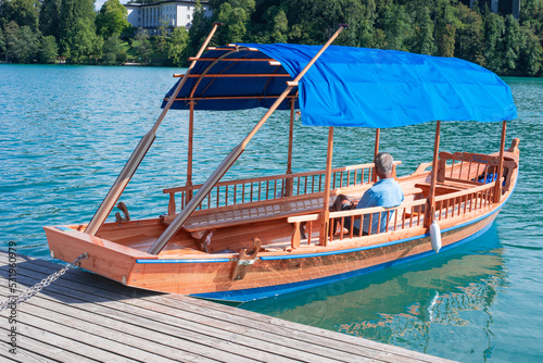 cute passenger boat with a awning on the lake Bled with a castle in the middle against the backdrop of the Slovenian Alps