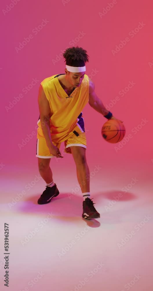 Vertical video of biracial male basketball player bouncing ball on pink background Vertical video of biracial male basketball player bouncing ball on pink background