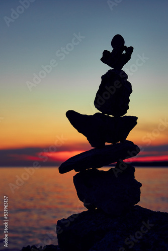 Silhouette of balanced zen stones on the ocean beach at sunset sunrise time.