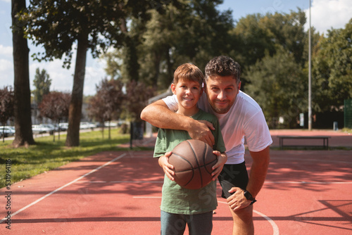 Father and son spending day together, playing basketball on a sunny day. They wear casual clothes © Stock Rocket