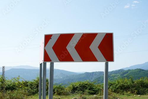 Close-up of a multi-turn road sign on a winding mountain road