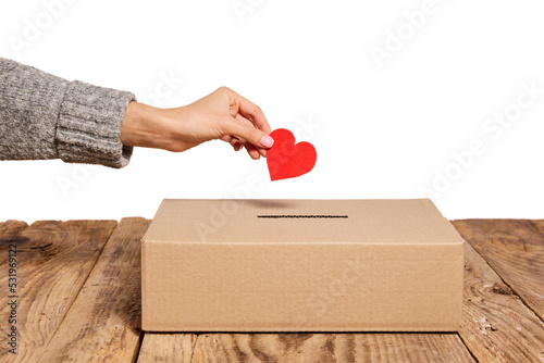 Charity. Red heart as symbol of peace, love is putting by female hand into slot of donation carton box. Concept of donorship, life saving or charity