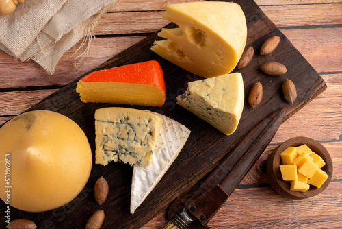 Varied cheese table, blue cheese Fontina Gruyer Cheese Teetilla in wooden table with red wine glass Pimentero oil and Round homemade fields of field and rustic knife photo