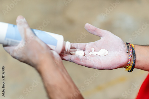 Hands pouring liquid magnesium from a bottle to practice climbing wall