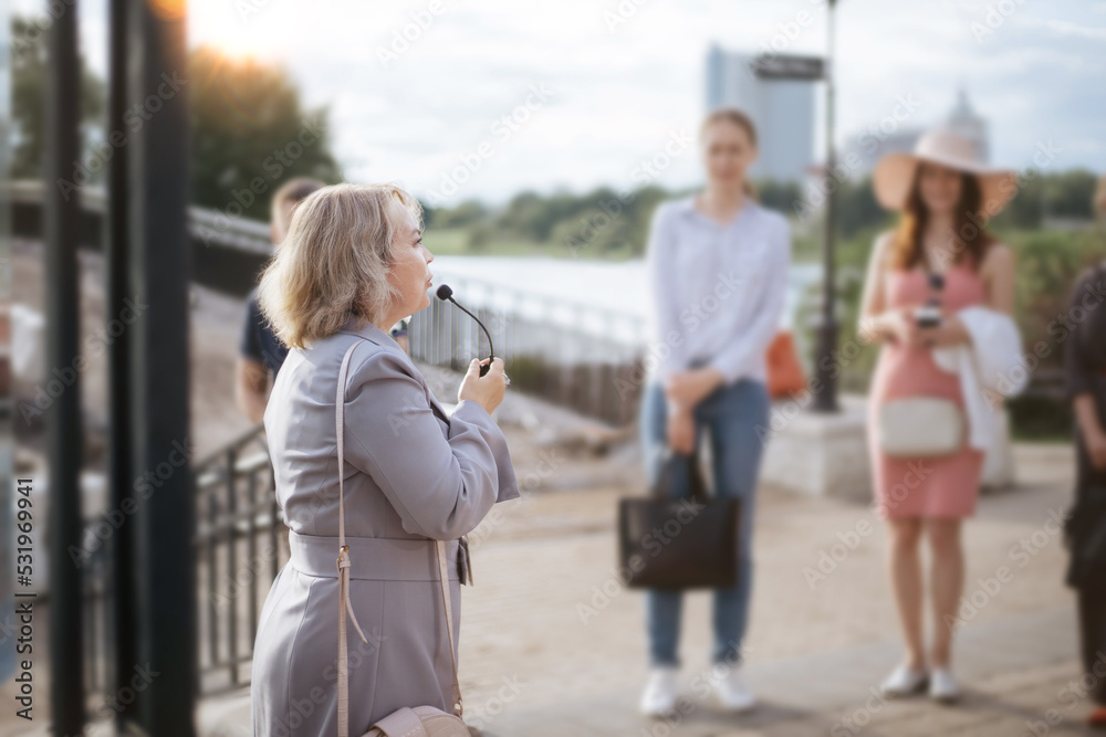female guide communicates with a group of tourists.