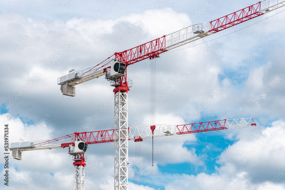 Two construction cranes against blue sky at sunny day Two construction cranes against blue sky at sunny day