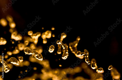 Drops of water splatter fly with yellow golden rays of the sun at sunset concept of freshness drink, watering the rain source of clean water fountain, copy space