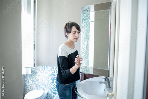 Young woman indoors at home doing morning routine in bathroom