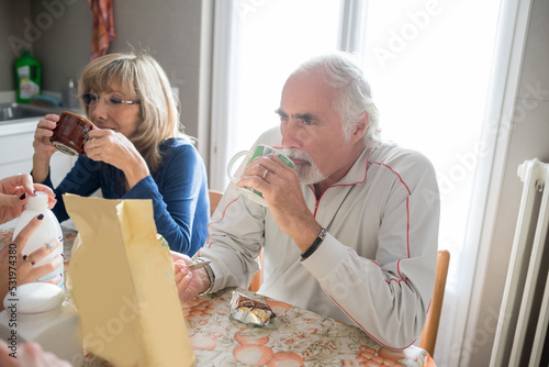 Senior adult married couple indoors at home having breakfast