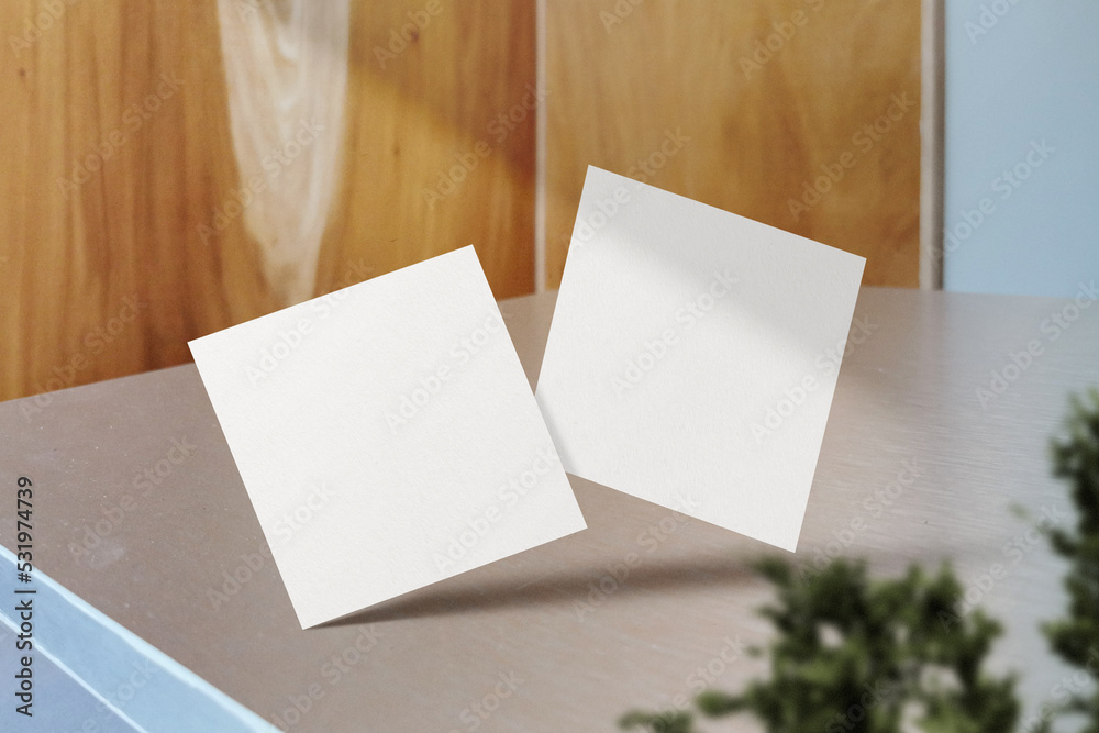 Clean minimal square flyer mockup floating on table with plant Clean minimal square flyer mockup floating on table with plant