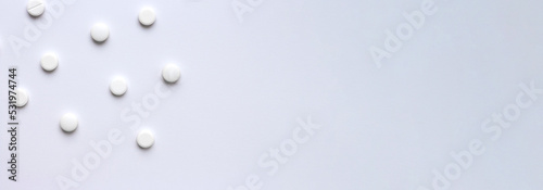 Medical background with pills on a white background. Medical pharmacy and medicine concept with copy space. Horizontal banner on a medical theme with space for text. A scattering of white pills. High