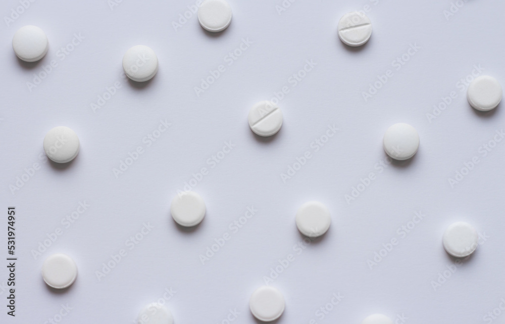 Many white tablets or pills on a white background. Medical pharmacy and medicine concept with copy space. Scattering of white round pills. High quality photo