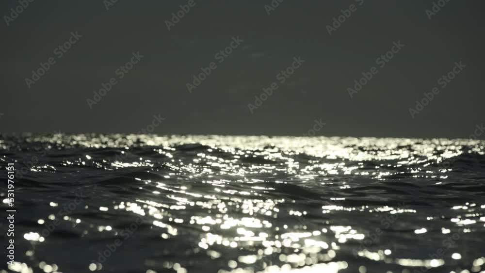 Sun reflecting on the ocean. Small waves on water surface in motion blur with bokeh lights from sunrise Sun reflecting on the ocean. Small waves on water surface in motion blur with bokeh lights from sunrise