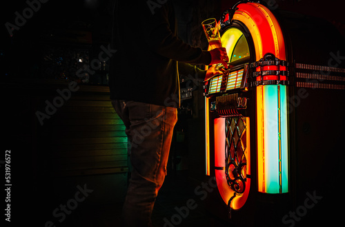 Man hand pushing buttons to play song on old Juke box, selecting records in bar photo