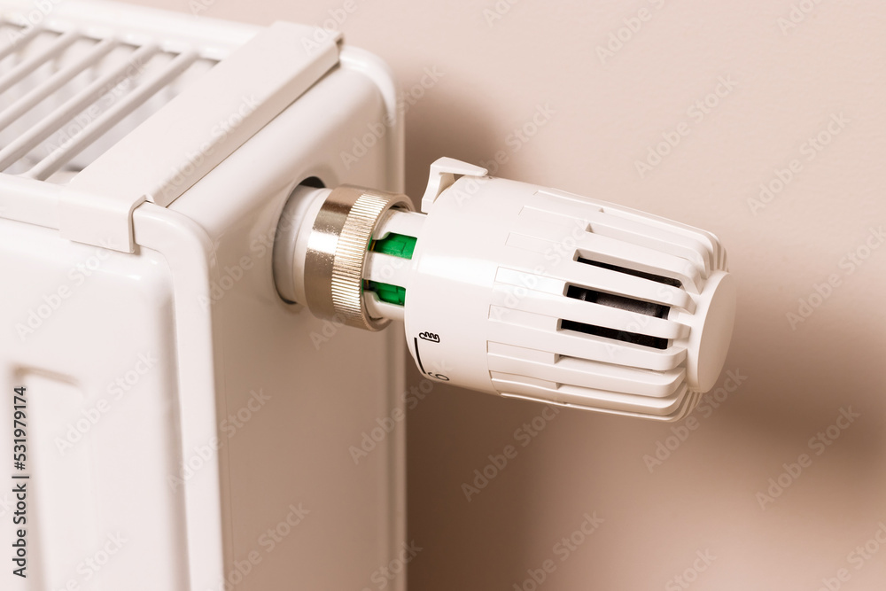 Control valve of home heating radiator in modern living room. Temperature regulator. Low temperature reduces heating costs Control valve of home heating radiator in modern living room. Temperature regulator. Low temperature reduces heating costs