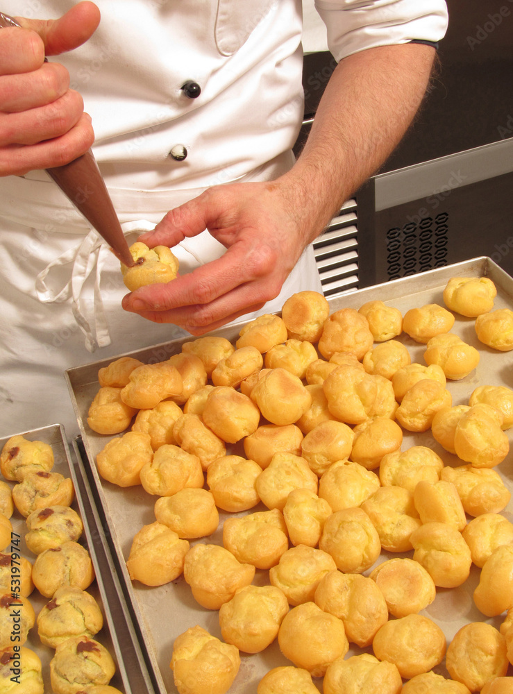 Pastry chef preparing and making chocolate sweets using cream pastry bag