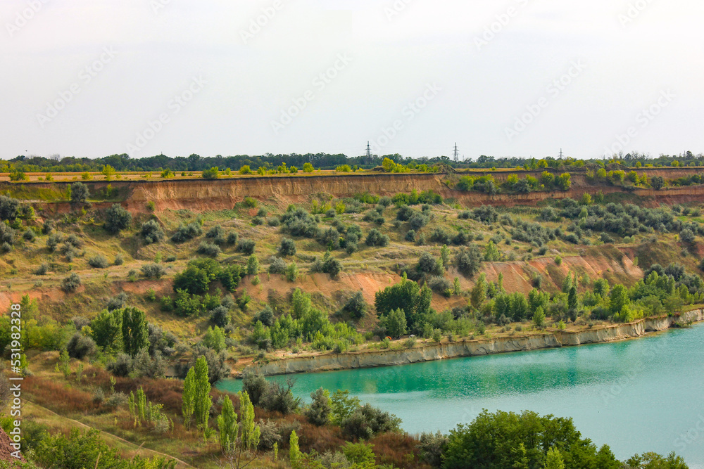 Photo of a sand pit with water overgrown with greenery. View from a distance