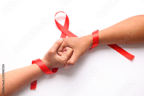 Two hands holds each other with red ribbon. Aids day concept