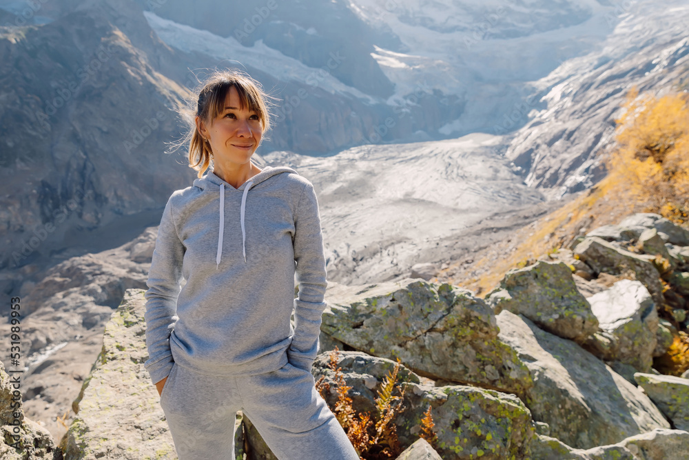 Naklejka premium Portrait of smiling woman in the mountains. Mountains with glacier and tourist girl