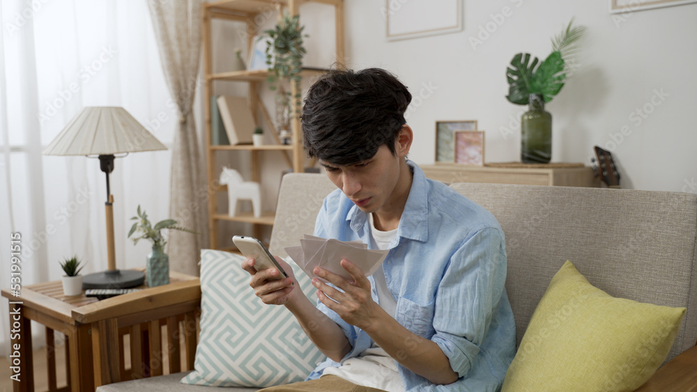 Overjoyed korean guy checking numbers on phone is covering mouth and