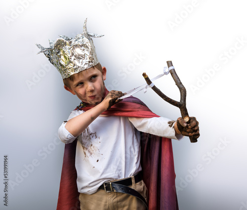 Dirty boy aiming with a slingshot