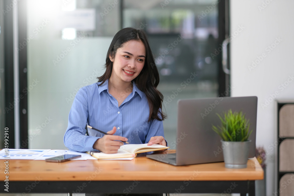 Charming asian businesswoman sitting working on laptop in office. Charming asian businesswoman sitting working on laptop in office.