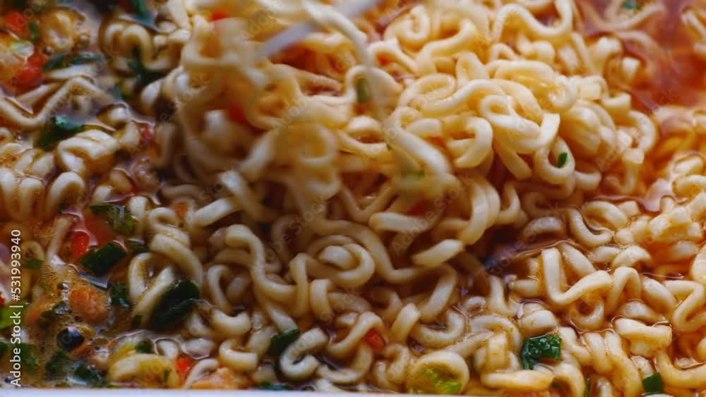 closeup cooked chinese instant pasta stir with a disposable fork.appetizing instant noodles on a plate.selective focus closeup cooked chinese instant pasta stir with a disposable fork.appetizing instant noodles on a plate.selective focus