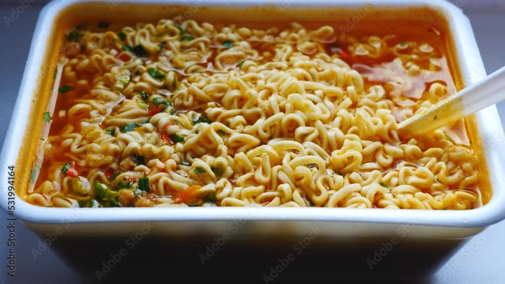 close-up appetizing ready-made instant noodles in a disposable container stir with a fork .instant lunch, seasoned noodles, ready-made soup close-up appetizing ready-made instant noodles in a disposable container stir with a fork .instant lunch, seasoned noodles, ready-made soup