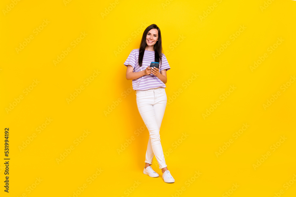 Full size photo of positive pretty lady arm hold telephone wear trendy outfit enjoy eshopping isolated on yellow color background Full size photo of positive pretty lady arm hold telephone wear trendy outfit enjoy eshopping isolated on yellow color background