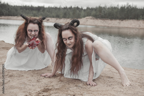 Fotografering Two horrible demons eating raw bloody meat