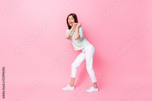 Photo of positive pretty lady trendy wear arm hold pull imaginary baggage empty space isolated on pink color background