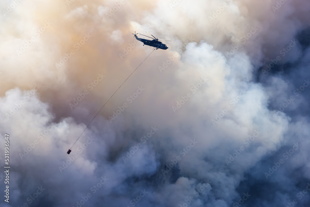 Wildfire Service Helicopter flying over BC Forest Fire and Smoke on the mountain near Hope during a hot sunny summer day. British Columbia, Canada. Natural Disaster Wildfire Service Helicopter flying over BC Forest Fire and Smoke on the mountain near Hope during a hot sunny summer day. British Columbia, Canada. Natural Disaster