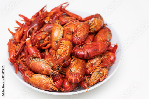Red boiled crayfish with lemon on the plate isolated on a white background.