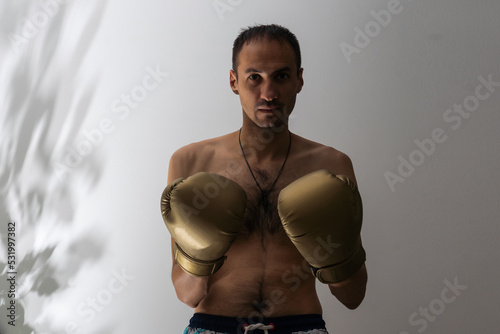 closeup shot of young naked boxer wearing protecting gloves. throwing puches in a boxing ring. grey background photo