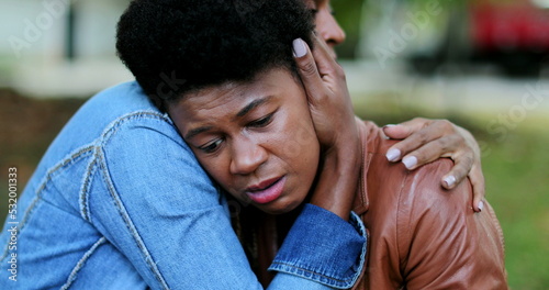 Depressed African woman, friend helping compassionate hug photo