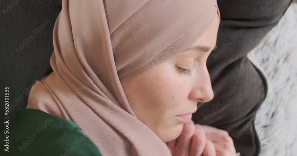 Beautiful young woman in hijab fell asleep on the sofa. Close-up face. Muslim woman was tired from work, she took a nap dressed on the couch at home in the living room. Beautiful young woman in hijab fell asleep on the sofa. Close-up face. Muslim woman was tired from work, she took a nap dressed on the couch at home in the living room.