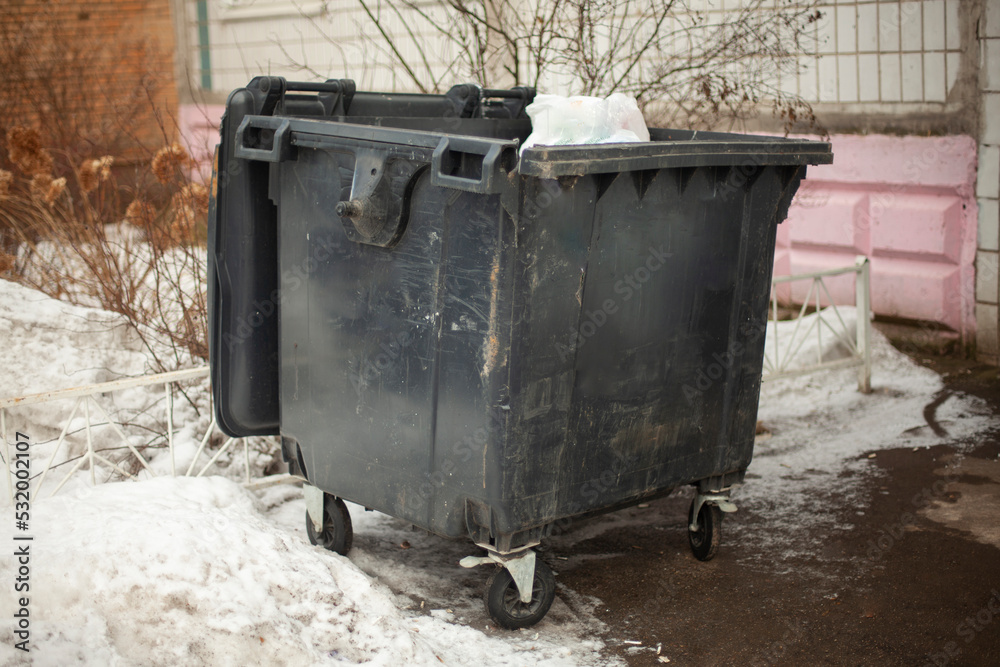 Black garbage can on street. Dirty container in ghetto. Waste garbage. Black garbage can on street. Dirty container in ghetto. Waste garbage.