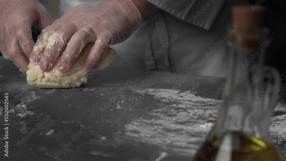 Baker is kneading a dough on a cutting board Baker is kneading a dough on a cutting board