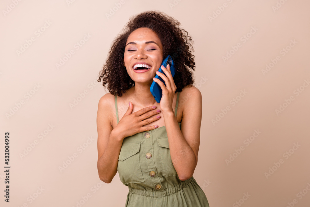Photo of adorable nice cheerful girl with curly hairdo dressed khaki overall hand on chest laughing isolated on beige color background Photo of adorable nice cheerful girl with curly hairdo dressed khaki overall hand on chest laughing isolated on beige color background