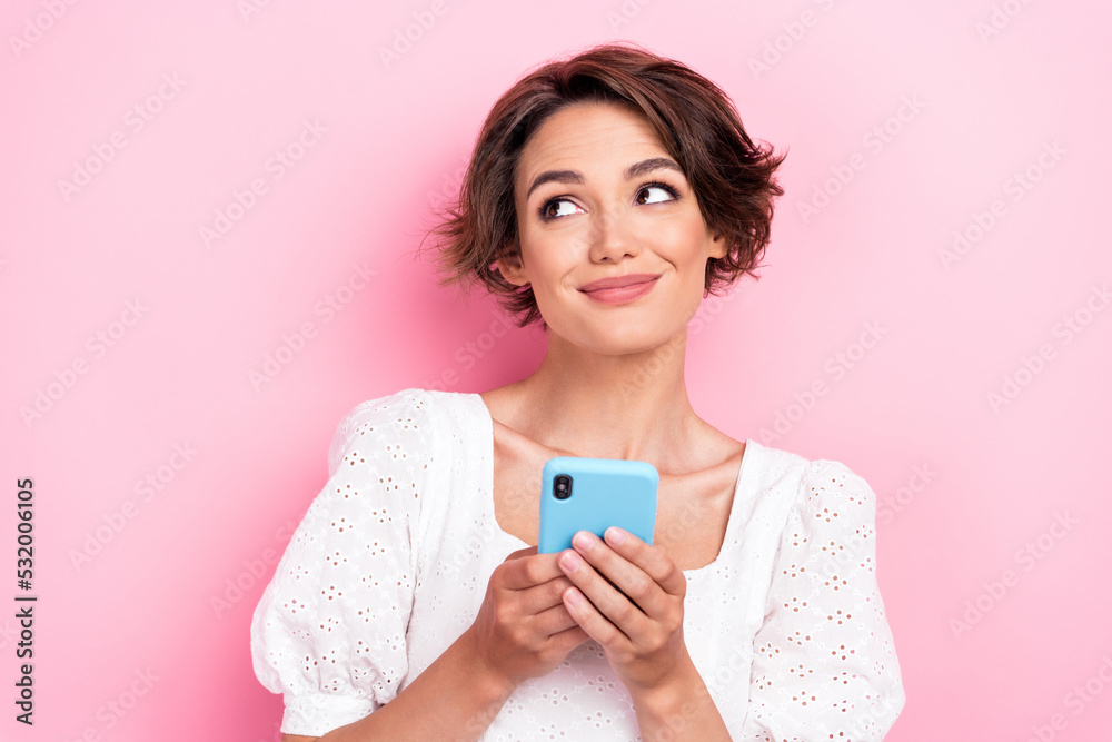 Photo portrait of stunning young girl smiling hold device look empty space wear stylish white outfit isolated on pink color background