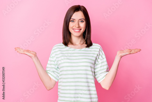 Photo of adorable gorgeous pretty girl bob hairdo dressed striped t-shirt hold palms compare products isolated on pink color background