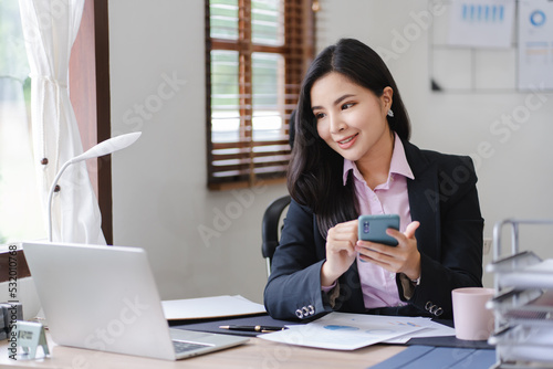 Asian businesswoman playing smartphone and working in his office © Daenin
