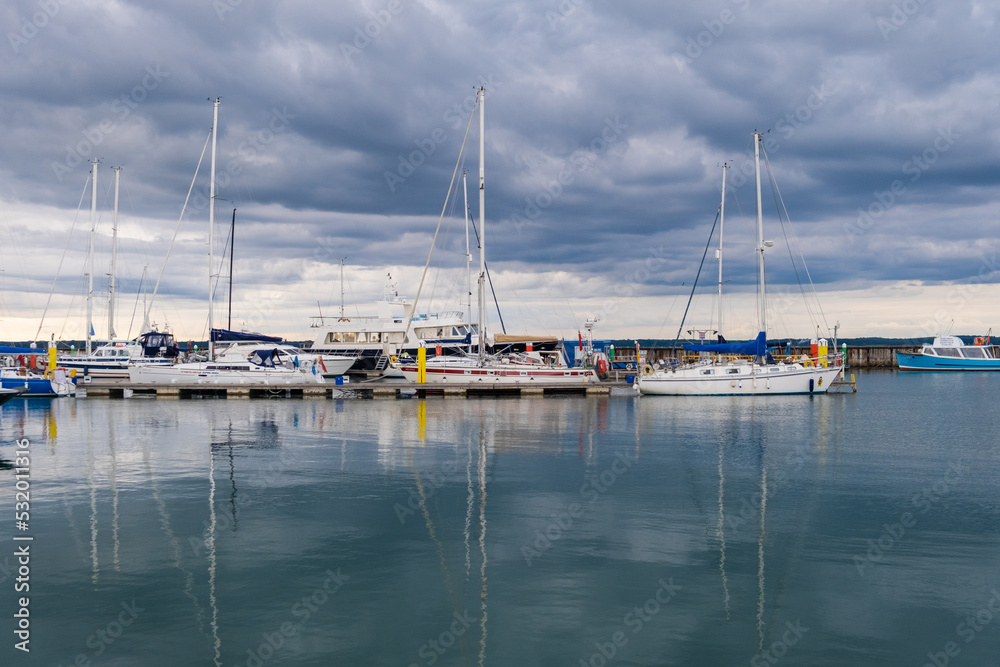 Sailing boats in a calm harbour with reflections on the water, UK