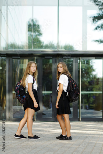 Back to school. First day of school. Two teenage girs at the entrance to the school feeling happy and excited.