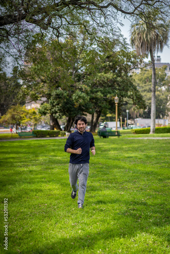 Portrait of handsome attractive mature bearded athletic latin man guy 40s in casual blue t-shirt running at a park