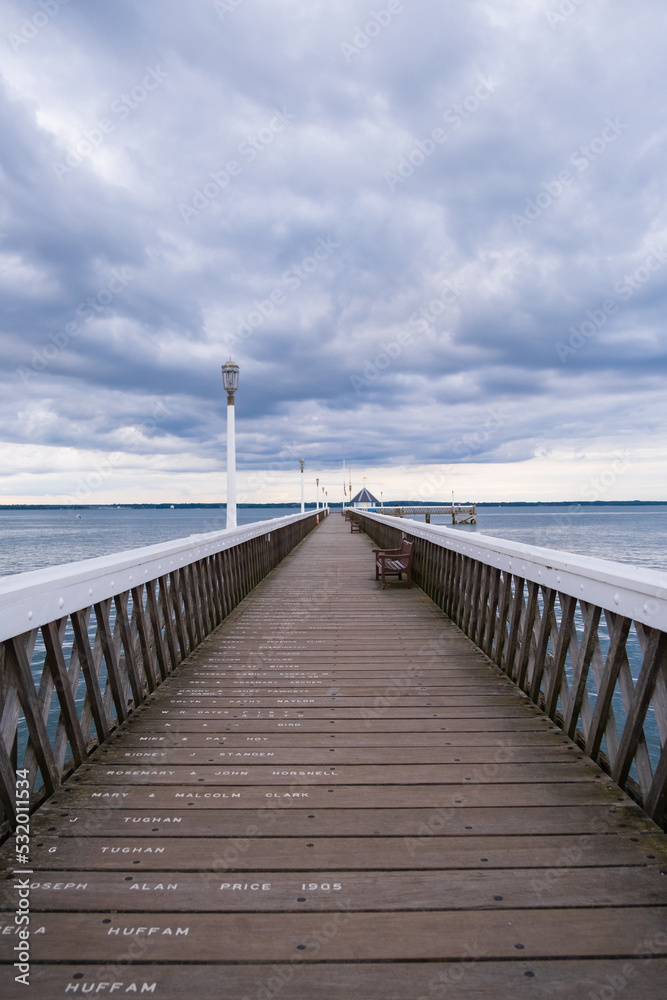 Wooden pier over the sea with benches along it Wooden pier over the sea with benches along it