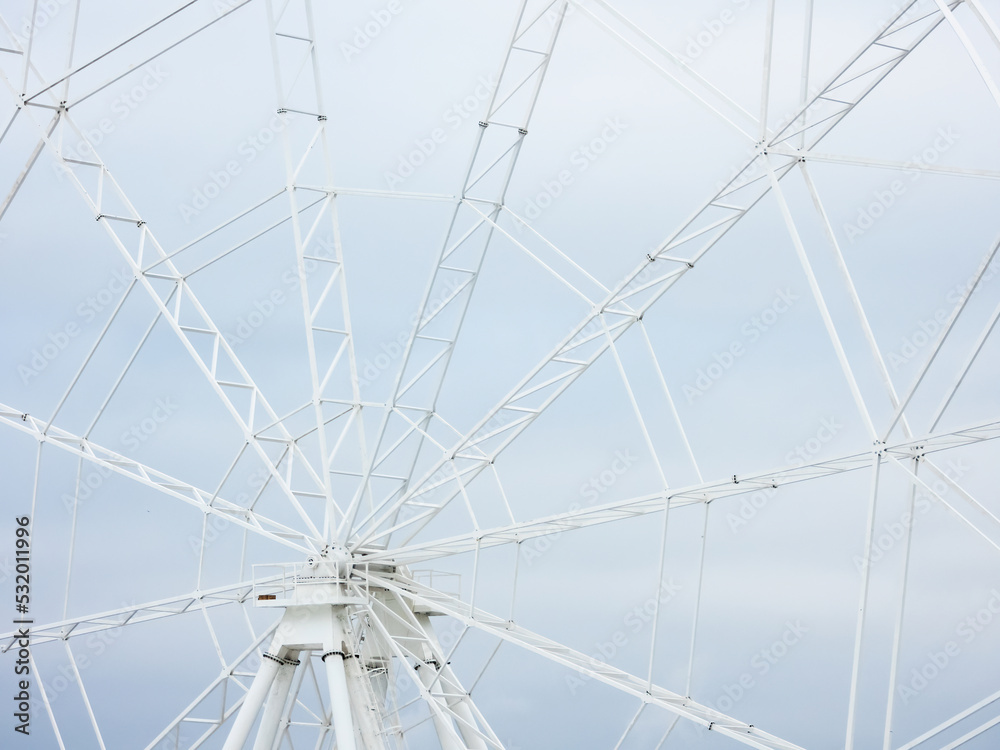 Fototapeta premium Fragment of ferris wheel under construction on a background of gray cloudy sky